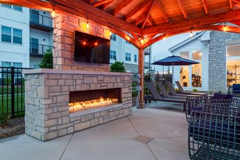 A patio with a stone fireplace and a red pergola.